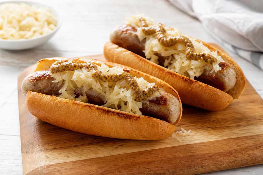 Browned bratwurst in toasted buns with mustard and sauerkraut