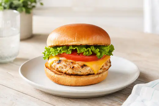 Chicken burger on a toasted bun with lettuce, tomato and cheese on a plate