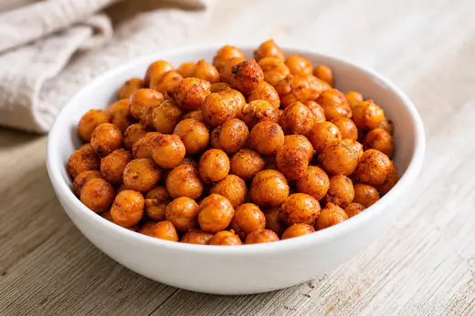 Golden crispy roasted chickpeas seasoned with paprika in a small white bowl
