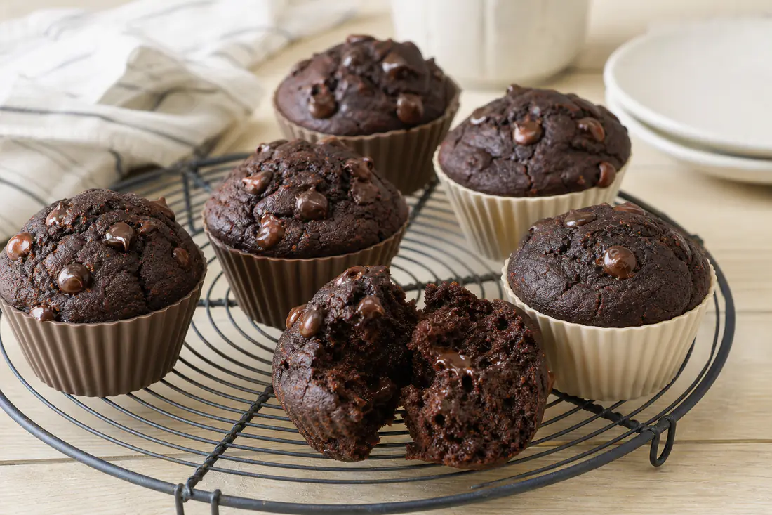 Dark double chocolate muffins with melted chocolate chips on top, in silicone cups