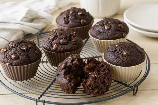 Dark double chocolate muffins with melted chocolate chips on top, in silicone cups