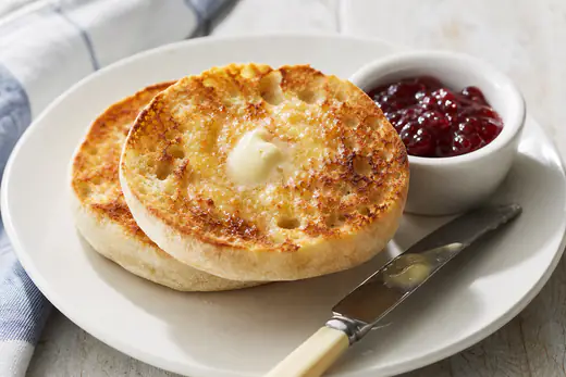 Toasted English muffin halves with melted butter on a white plate