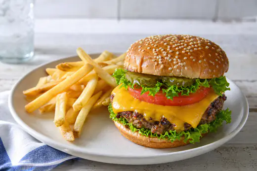 Cheeseburger on a toasted bun made from a frozen patty, served with lettuce and tomato