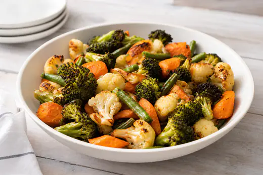 Roasted mixed vegetables with browned edges in a white bowl