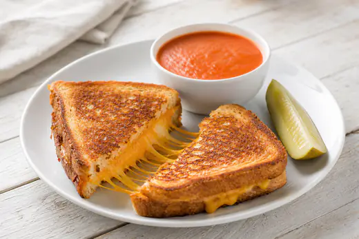 Golden grilled cheese sandwich cut in half with melted cheddar stretching between the halves