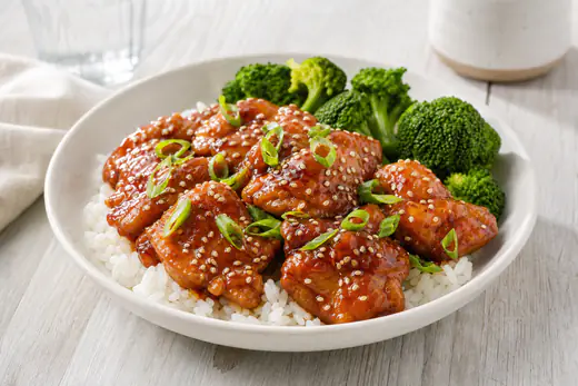 Glazed honey garlic chicken thighs with sesame seeds and broccoli on a plate