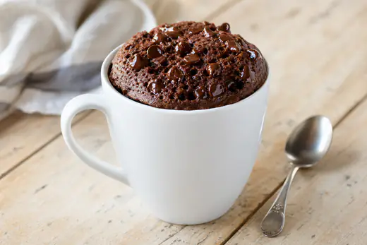 Chocolate mug cake in a white ceramic mug with chocolate chips and a spoon