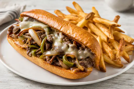 Philly cheesesteak sandwich on a toasted hoagie roll with melted provolone, peppers and onions