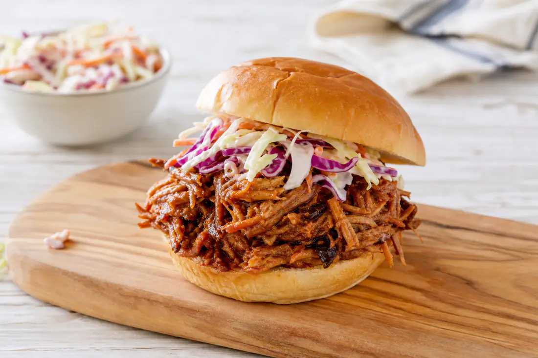 Shredded barbecue pulled pork piled on a toasted bun with coleslaw