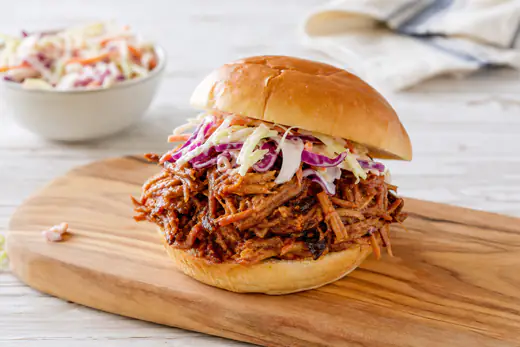 Shredded barbecue pulled pork piled on a toasted bun with coleslaw