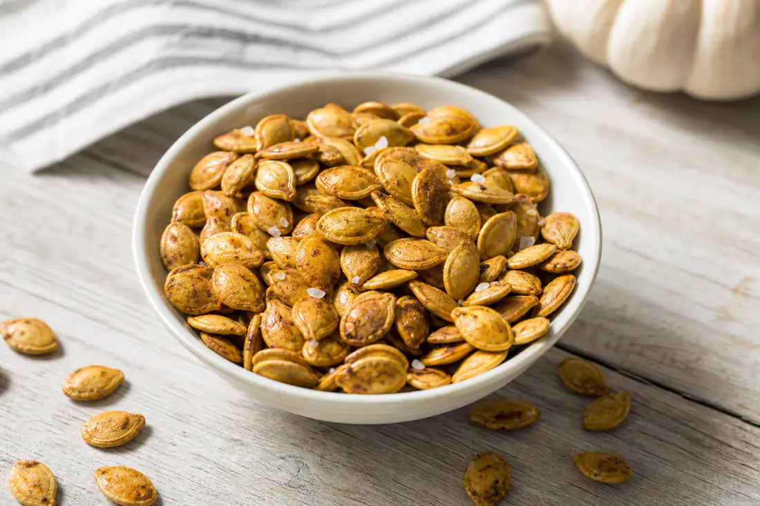 Golden roasted pumpkin seeds with sea salt in a small white bowl