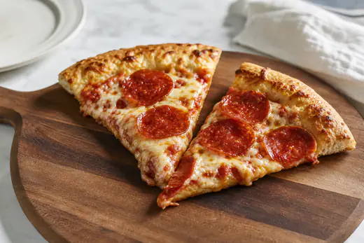 Reheated pizza slices with crisp crust and melted cheese on a wooden board