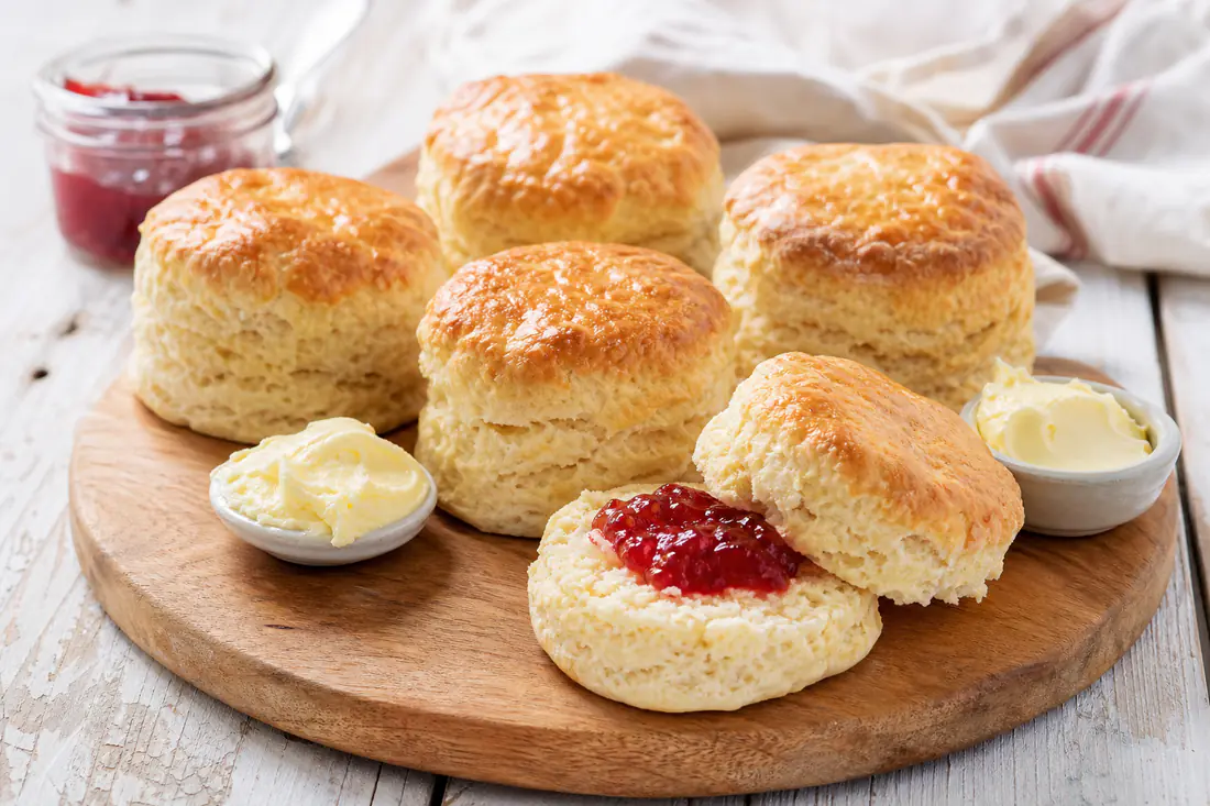Golden buttermilk scones with one split open, with butter and jam