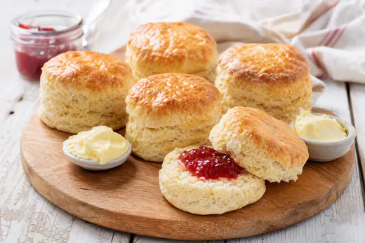 Golden buttermilk scones with one split open, with butter and jam
