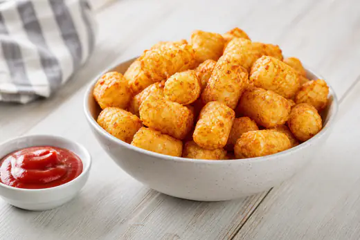Golden crispy tater tots in a bowl served with ketchup