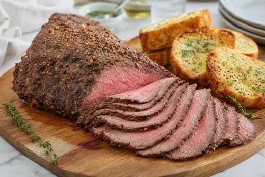Sliced tri tip roast with a spice crust on a wooden cutting board