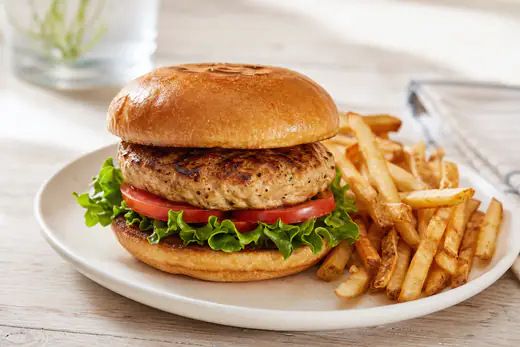 Turkey burger on a toasted bun with lettuce and tomato next to a pile of fries