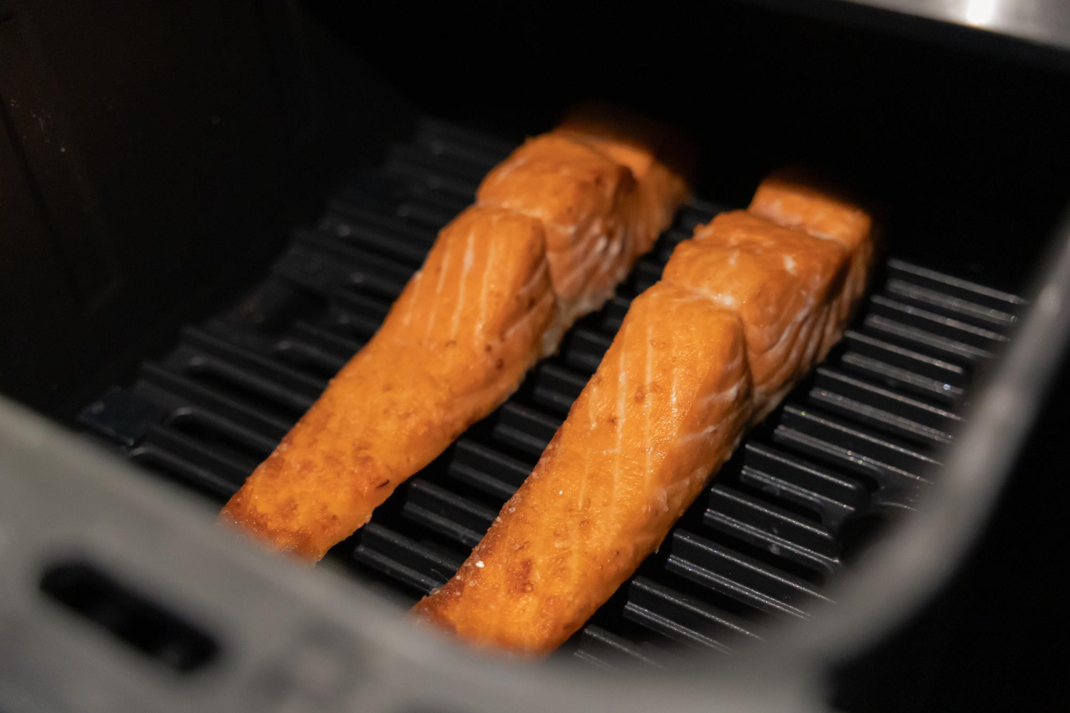 Crispy salmon pieces in air fryer basket